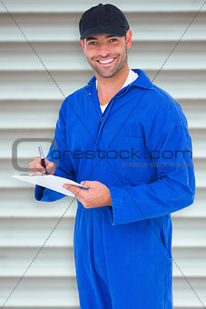 Composite image of handyman in blue overall writing on clipboard