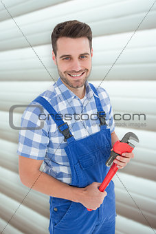 Composite image of confident young male repairman holding monkey wrench