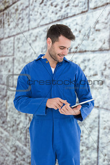 Composite image of male mechanic using digital tablet