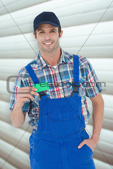Composite image of confident plumber showing green card