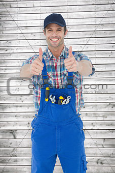 Composite image of confident plumber showing thumbs up sign