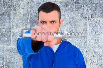 Composite image of confident male mechanic holding spanner