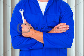 Composite image of male mechanic holding spanner on white background