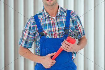 Composite image of cropped image of plumber holding monkey wrench