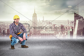 Composite image of crouching handyman holding power drill