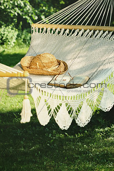 Crocheted hammock with straw hat and book