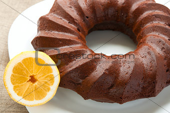 Chocolate honey cake and half of lemon on white plate close up