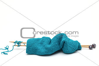 blue yarn with knitted fabric and knitting needles
