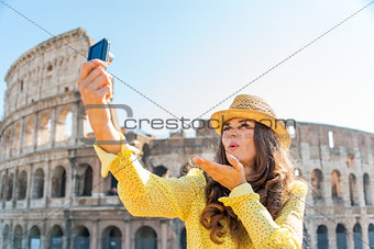 Woman tourist taking selfie blowing kisses at Rome Colosseum