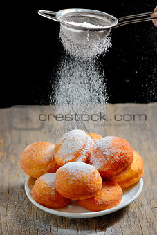 pours sugar over donuts