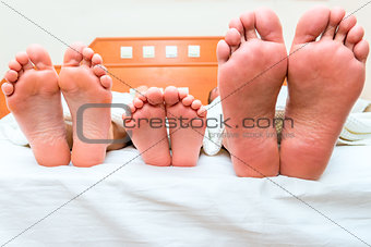 family of three people sleeping in one bed, feet close-up