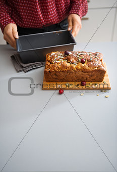 Woman's hands holding a baking tin with cranberry and seed loaf