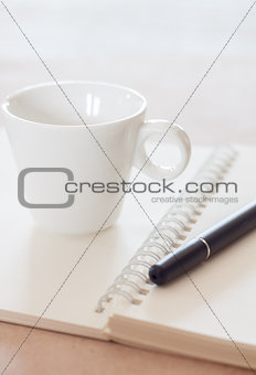Pen and spiral notebook with coffee cup
