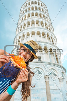 Woman biting slice of pizza by Leaning Tower of Pisa