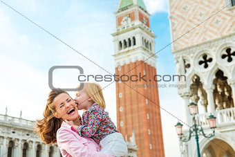 Laughing mother being kissed by daughter on St. Mark's Square