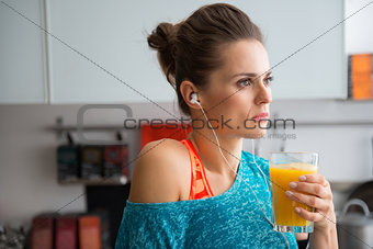 Closeup of woman in profile wearing workout gear holding juice