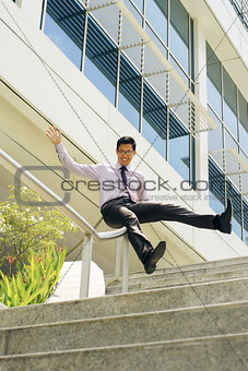 Happy Chinese Businessman Going Downstairs Sliding On Rail