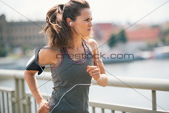 Jogging woman on bridge listening to music