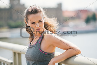 Woman jogger resting listening to music looking over shoulder