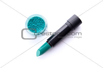 Top view of a lipstick and eye shadow in jar in bright teal gree