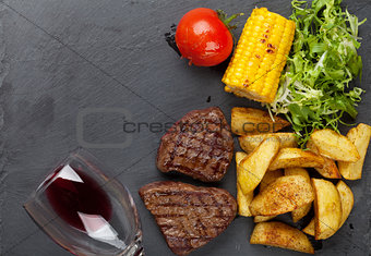 Beef steak with grilled potato, corn, salad and red wine
