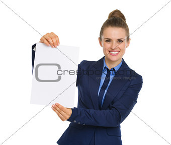 Businesswoman smiling and holding up a blank piece of paper
