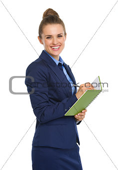 Happy businesswoman smiling at camera, holding notebook and pen