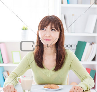 Asian girl eating breakfast and thinking