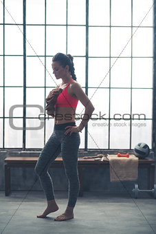 Fit woman in profile wiping sweat from chest in loft gym