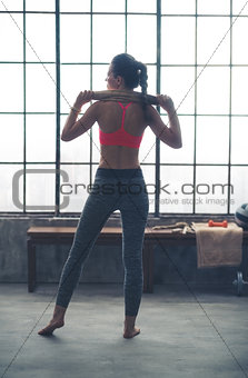 Rear view of fit woman holding towel across shoulders in gym