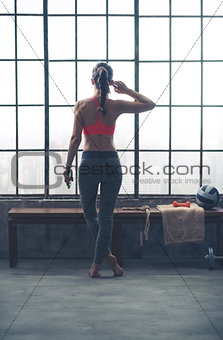 Rear view of fit woman in loft gym listening to music