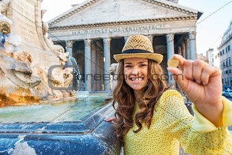 Happy woman tourist holding coin to throw in Pantheon fountain