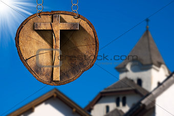 Wooden Cross on Tree Trunk with Church
