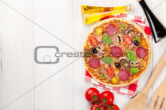Italian pizza with pepperoni, tomatoes, olives and basil