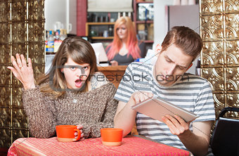 Insulted Woman Next to Man on Tablet