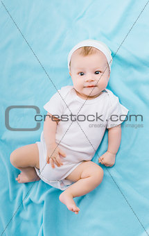 baby in hat lying on a blue blanket
