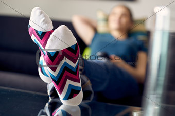 Woman With Feet On Table Watching Film TV At Home