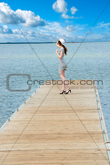 dreaming girl in elegat dress on lakes pier