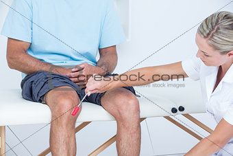 Doctor checking reflexes of the knee of her patient