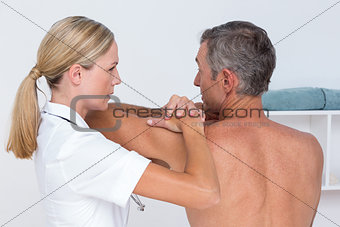 Doctor examining her patient shoulder