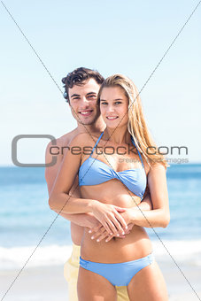 Happy couple in swimsuit looking at camera and embracing