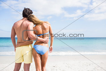 Happy couple embracing and looking at the sea