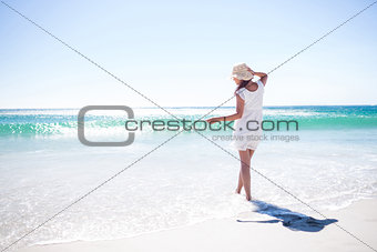 Pretty brunette wearing straw hat and walking in the water