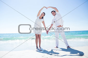 Happy couple forming heart shape with their hands