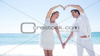 Happy couple forming heart shape with their hands