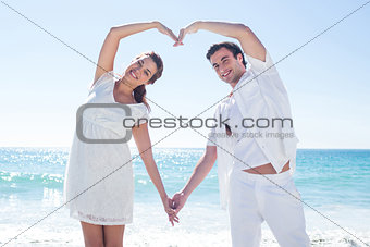 Happy couple forming heart shape with their hands