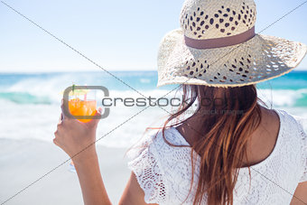 Brunette wearing straw hat and holding a cocktail