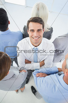 Businessman looking at camera with his colleague around him