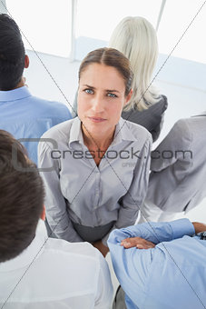 Unhappy businessman looking at camera with her colleague around her