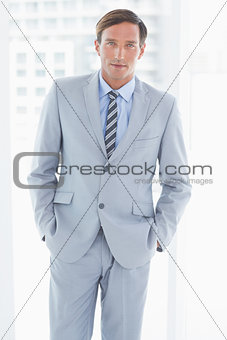 portrait of businessman looking at camera with hands in pockets